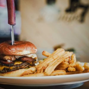 Two short rib and brisket ground beef patties, cheddar cheese, thick-cut smoked bacon, "Big Mozz" cheese stick, jalapenos, caramelized onion, spicy garlic aioli, fried egg, served on a potato bun.
