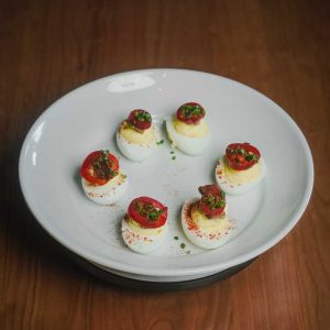 Six eggs topped with candied bacon, red jalapenos, smoked paprika